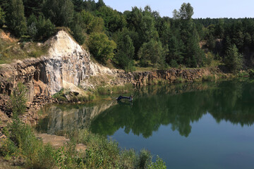 Fototapeta premium Landscape photo with a view of a quarry filled with water and basalt rocks around in the village of Bazaltove, Rivne region, Ukraine