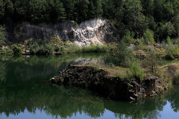 Landscape photo with a view of a quarry filled with water, island with greenery and basalt rocks in the village of Bazaltove, Rivne region, Ukraine
