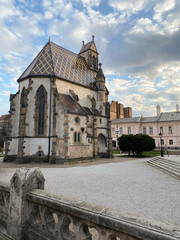 Obraz premium A historic church with a distinctive tiled roof, surrounded by a quiet plaza.
