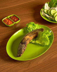 Fried Catfish with Sambal and Fresh Vegetables A Classic Indonesian Dish Featuring Crispy Fried Catfish Served with Spicy Chili Sauce and Vegetables.