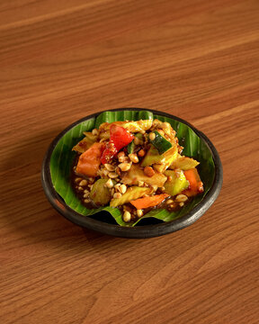 Spicy Rujak Ulek Served on Banana Leaf Traditional Indonesian Fruit Salad with Chili Sauce, Fresh Ingredients, and Rustic Natural Leaf Presentation.
