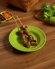 Traditional Indonesian Delicacy, Chicken Liver and Gizzard Skewers Served with Fresh Vegetables and Spicy Sambal on the Side.