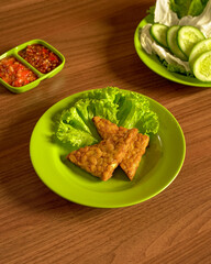 Crispy Fried Tempeh Served With Assorted Fresh Vegetables And Spicy Sambal On The Side, A Classic Sundanese Dish Full Of Flavor And Crunch.