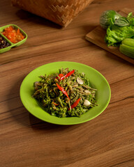 Stir-Fried Papaya Flowers Served with Fresh Vegetables and Spicy Sambal on the Side, A Unique Indonesian Dish Full of Bitterness and Bold Flavors.