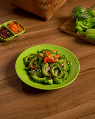 Sauteed Bitter Melon Served with Fresh Vegetables and Spicy Sambal on the Side, A Traditional Indonesian Dish with Unique Flavor and Nutritional.