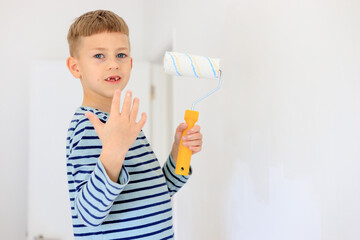 A young boy renovating a room, sanding the walls with sandpaper and painting them white with a...