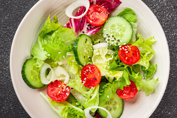 Salad vegetable tomato, cucumber, lettuce, green leaf lettuce, onion appetizer vegetable dish fresh gourmet food background rustic food top view copy space keto and paleo diet vegetarian vegan food