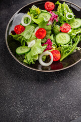 Salad vegetable tomato, cucumber, lettuce, green leaf lettuce, onion appetizer vegetable dish fresh gourmet food background rustic food top view copy space keto and paleo diet vegetarian vegan food