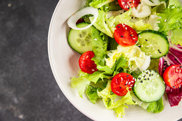 Salad vegetable tomato, cucumber, lettuce, green leaf lettuce, onion appetizer vegetable dish fresh gourmet food background rustic food top view copy space keto and paleo diet vegetarian vegan food