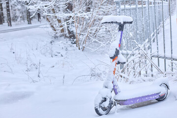 Winter s stillness blankets a forgotten electric scooter, a poignant scene of urban life paused by heavy snowfall, evoking a sense of quiet isolation.