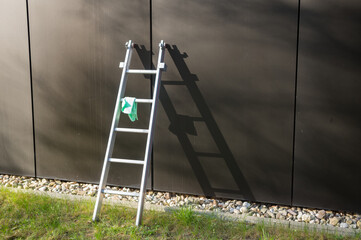 Metal ladder leaning against building with cleaning cloth hanging on it © Ulrich