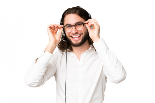 Telemarketer man working with a headset over isolated chroma key background with glasses and surprised