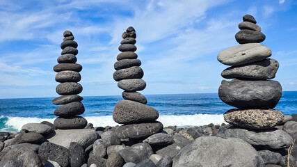 Balanced Stone Cairns on Rocky Shoreline with Ocean Waves