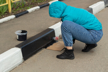 Painting road curb. Black paint and brush.