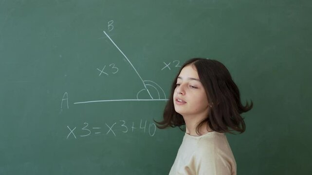 A teenage girl solves a math problem on the board during a math lesson