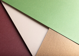 Paper background with matte texture. Layered diagonal sheets in burgundy, maroon, pastel green,...