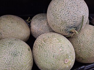 Cantaloupe pile: Pale green melons with textured rind, close-up still life.