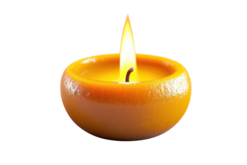 A glowing orange candle flame illuminates a unique citrus shaped candle against a stark black background warm light