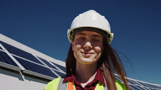 Female engineer standing confidently on rooftop with solar panels