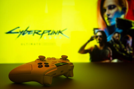 Dhaka, Bangladesh- 13 April 2025: A close-up of a white gamepad with the cyberpunk 2077 seen on screen in the background.
