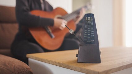 Musician practicing guitar using a metronome for perfect timing