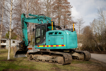 Large green excavator on grassy ground near construction site