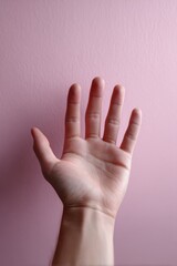An inviting hand extended against a soft pink backdrop inspires a sense of calm and unity in a clean, understated setting.