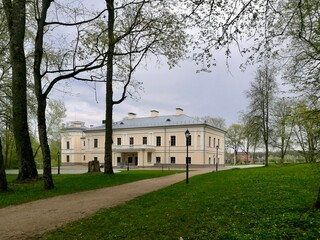 Jasiunai manor in Lithuania. Historic manor house with a neoclassical architecture, featuring pale yellow and white tones. The building has rectangular windows and a decorative balustrade on the roof.