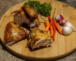 Roasted Chicken, chili, garlic, onion and parsley on wooden cutting board