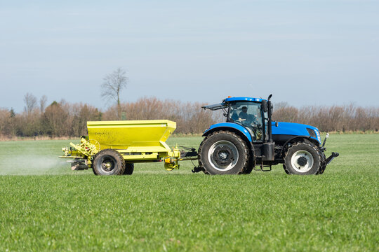 Tractor with fertiliser spreader in the grain field