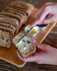Person spreading butter on a slice of bread to make sandwich