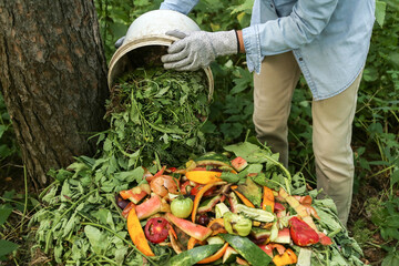 Zero waste, composting concept. Compost heap pile with bio waste. Farmer hands put weeds grass...