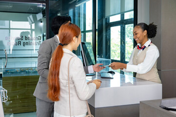 Obraz premium Couple passengers are getting their boarding pass from airline ground crew at departure gate into the airplane for final inspection before boarding the plane