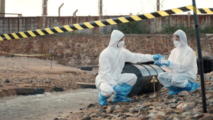 Ecologist sampling water from the river with test tube, Scientist or Biologist in a protective suit...