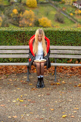 Young woman reads peacefully on a park bench on a sunny day in autumn