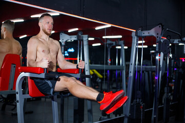 Muscular man doing exercises on horizontal bar in modern gym. Training for endurance and strength.