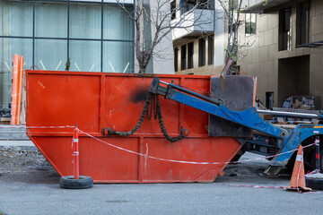 Large red construction waste container near modern building during renovation