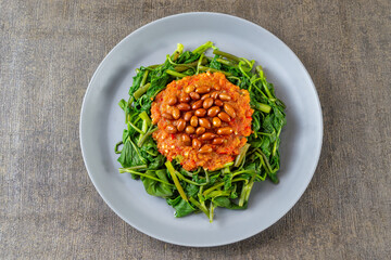 Plecing Kangkung is a refreshing and spicy Indonesian salad made from blanched water spinach (kangkung) topped with a flavorful chili sambal. Originating from Lombok