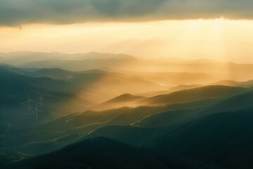 Sun rays over misty green mountains showcasing nature's beauty and wind turbines
