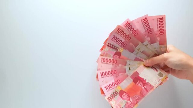 Asian Hand Holding Fanned Colorful Rupiah Banknotes Waving Slowly Front Bright White Background Representing Wealth Finance Bonus Prize Riches Prosperity Moneyflow Currency Income Reward Gift Success