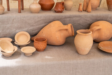 A table with many different types of pottery, including bowls, vases, and cups. The table is covered in a cloth and the pottery is arranged in a way that makes it easy to see