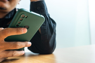 Person Using Green Mobile Phone with Cover at Wooden Table Indoors
