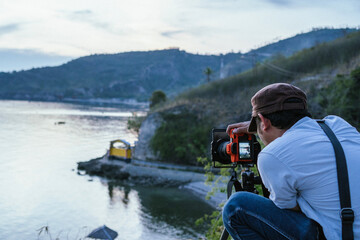 Photographer Capturing Coastal Scenery with Professional Camera and Tripod