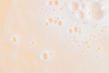 Abstract yellow orange color clean soapy foam texture. Shampoo foam with bubbles background