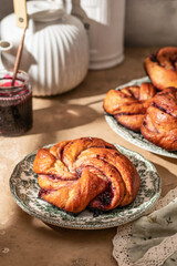Fresh baked brioche jam swirl buns on brown kitchen table in bright morning light