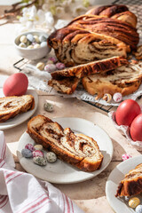 Easter baking. Homemade Easter Chocolate babka or brioche bread cutted with easter eggs and flowers in bright sunlight. Sweet yeast dough with chocolate filling