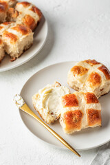 Traditional Easter hot cross buns on white plate with butter on white background. Delicious Easter breakfast