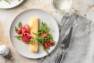 Delicious french omelette with cheese served with fresh vegetables and ham. Healthy diet food concept. Top view