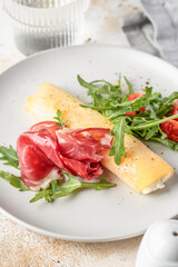 Delicious french omelette with cheese served with fresh vegetables and ham close up. Healthy diet food concept