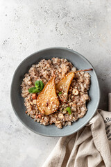 Wholegrain oatmeal porridge with caramelized pear, nuts and honey on white table isolated, healthy food for breakfast